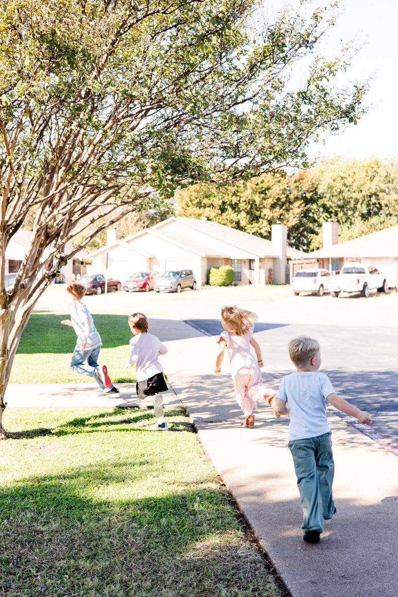 Children walking and running along a sidewalk outside the church