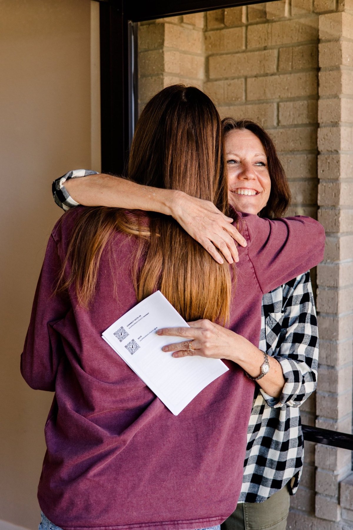 A greeter hugging a guest at the church door.