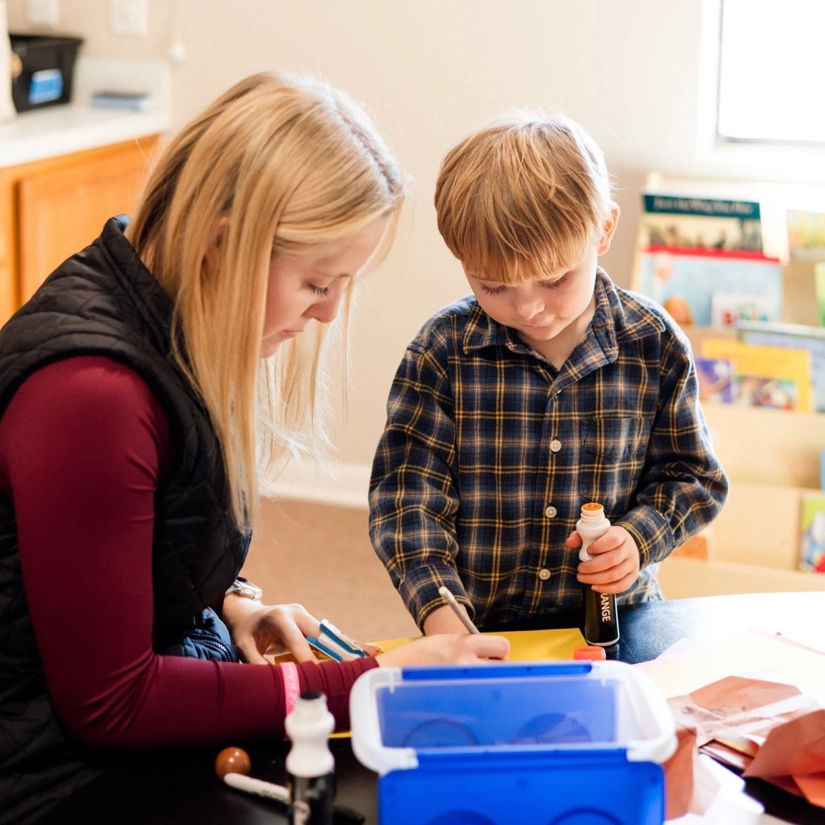 A volunteer helping a preschool boy with a craft