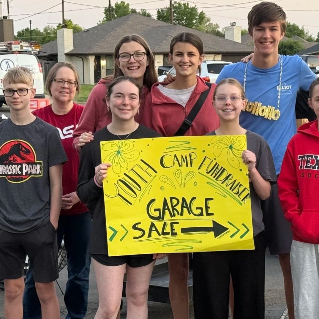 Students standing together holding a garage sale sign during a Student Ministry fundraiser